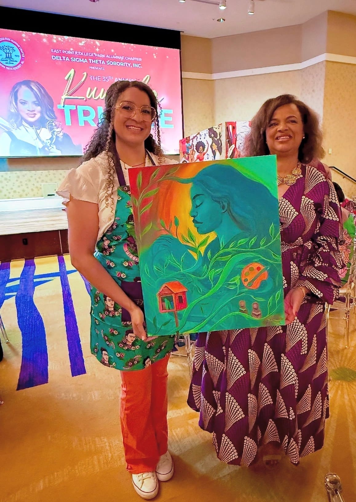 Reinilda holding a finished live painting at a Kwanzaa tribute event
