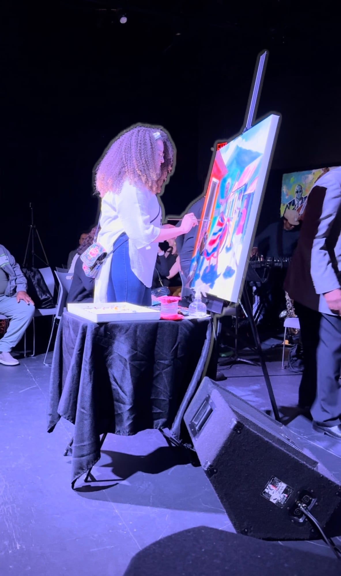 Reinilda painting live on stage while a band performs